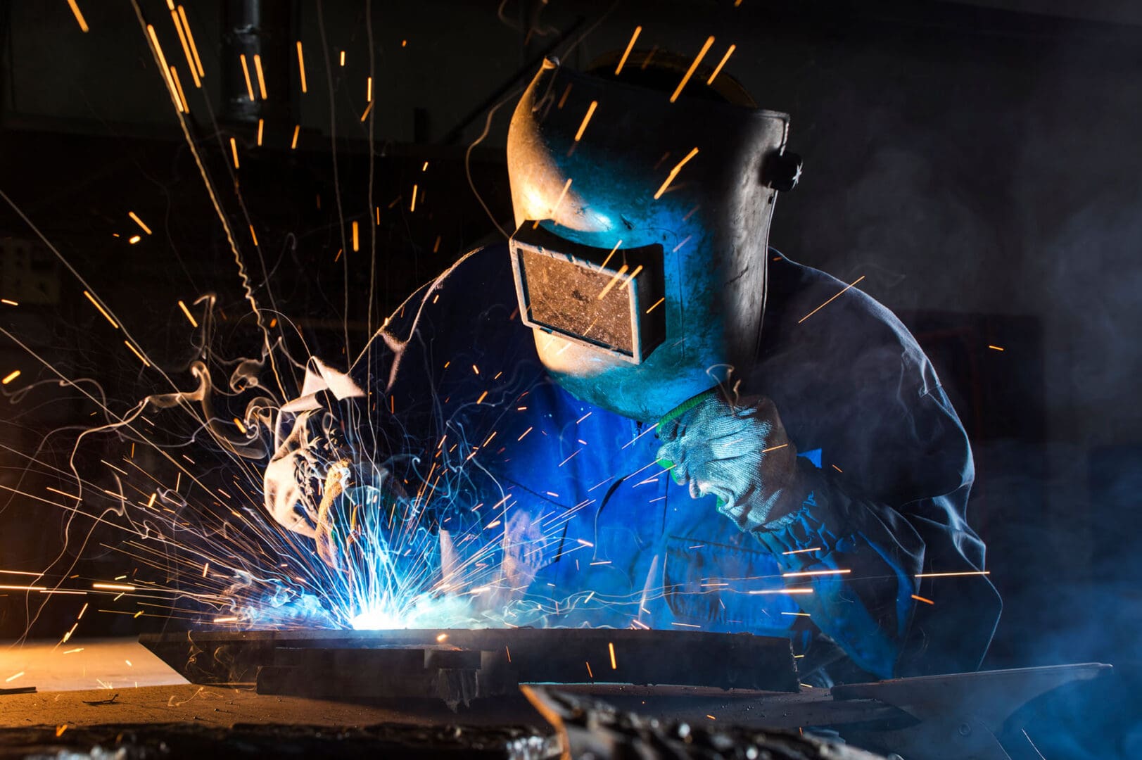 A man welding with many sparks flying around him.