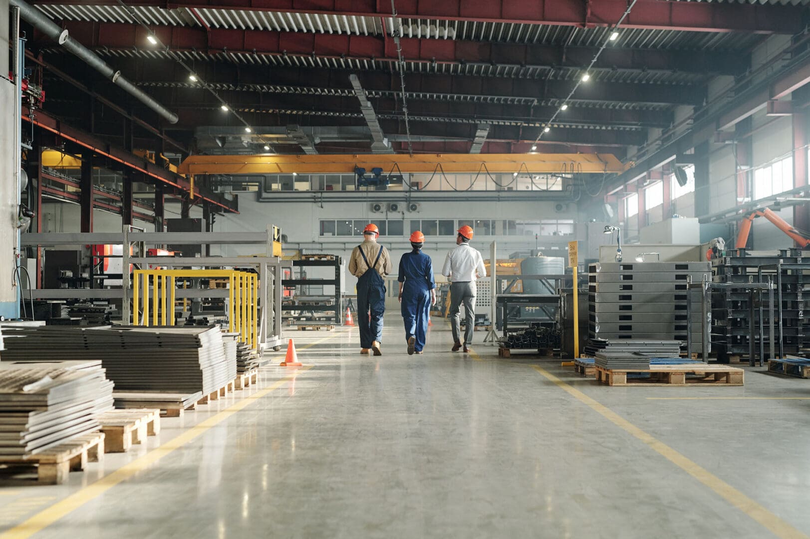 Three men in a factory walking down the aisle