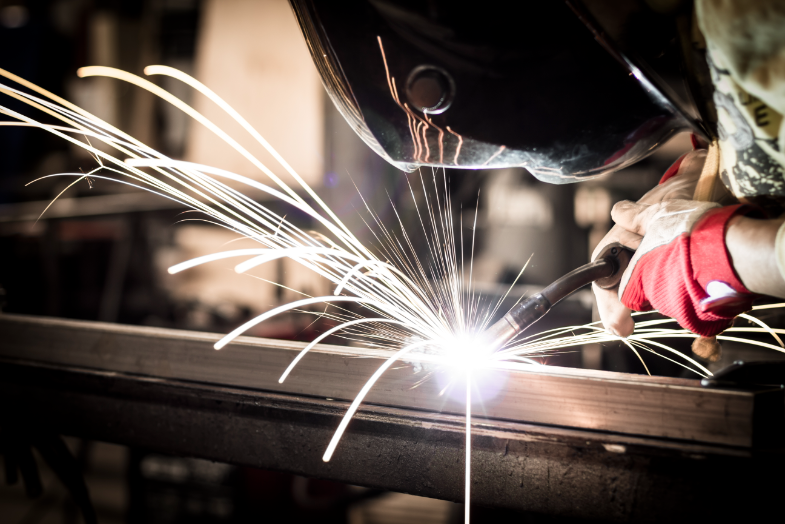 A person welding metal with sparks flying.