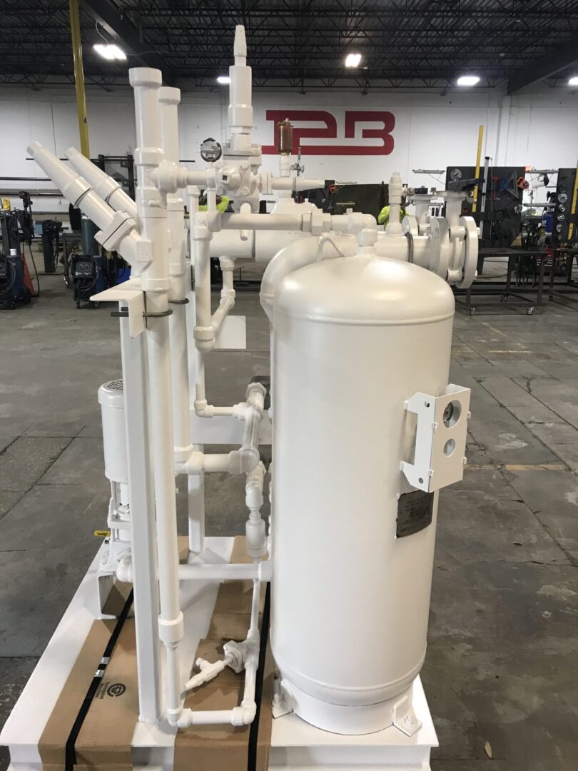 A white tank sitting in a warehouse next to pipes.