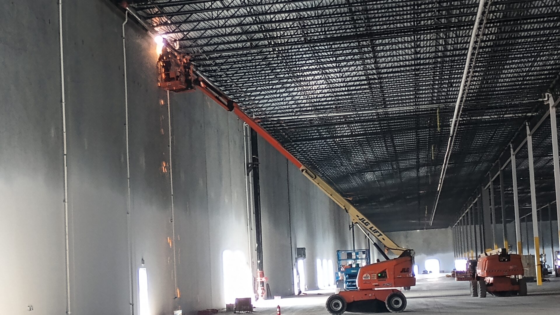 A man on a cherry picker working in an industrial building.