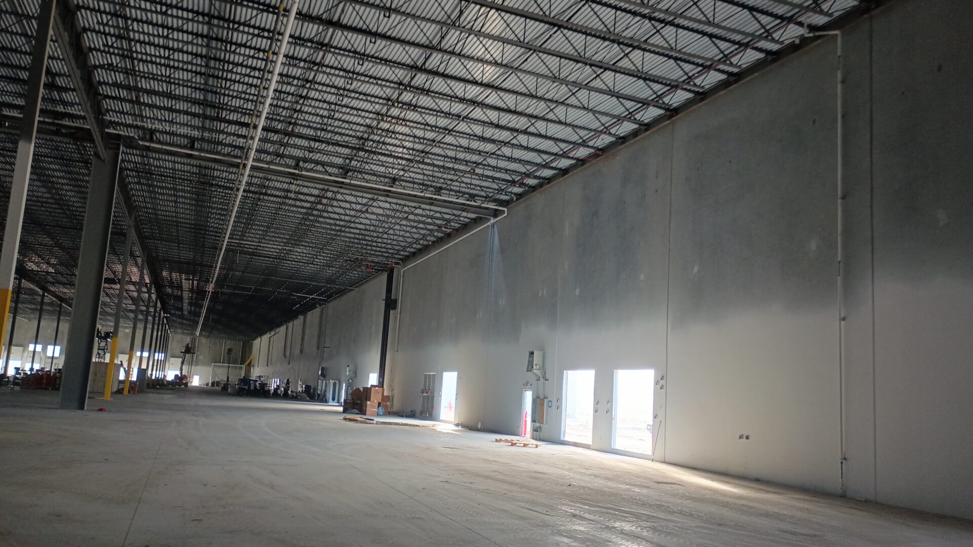 A warehouse with many windows and lights on the ceiling.