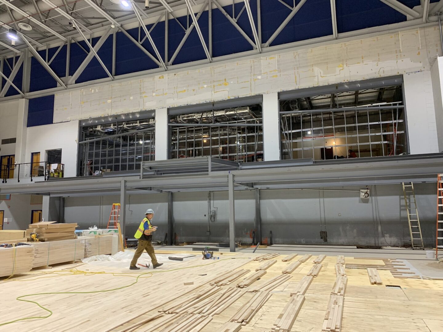 A man walking across the floor of an indoor arena.